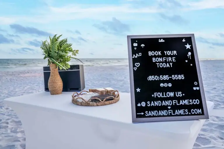 A beachside bonfire booking sign on a table along 30A in Santa Rosa Beach with contact information for Sand & Flames Co.