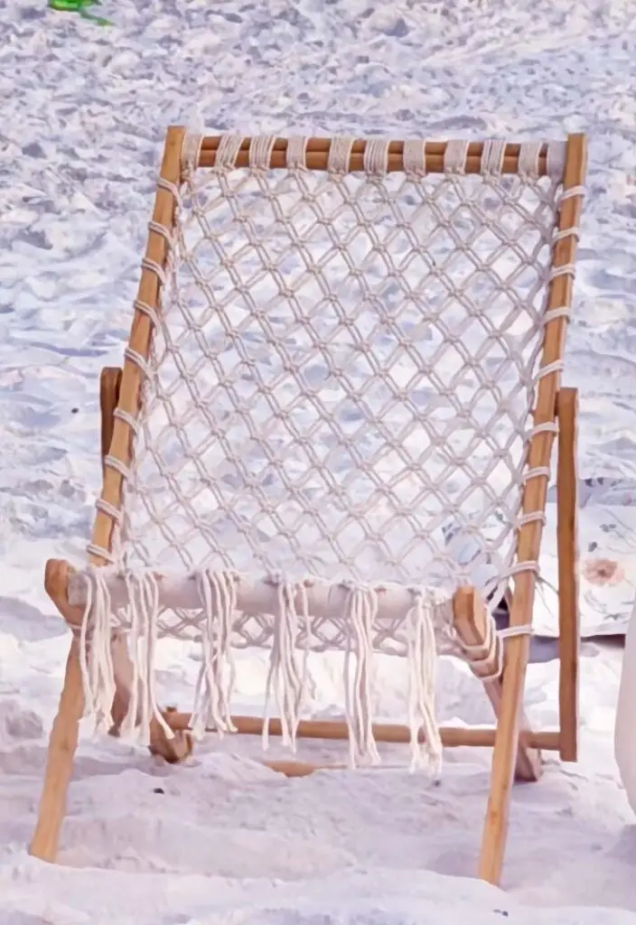 A bohemian woven wooden sling chair with fringe on the sand for a beachside bonfire in Miramar Beach along 30A.